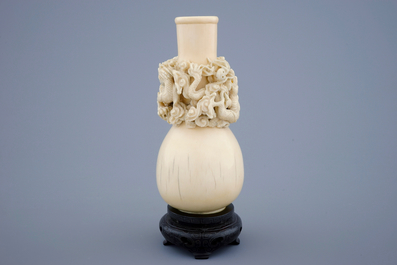 A Chinese carved ivory dragon vase on a wooden base, early 20th C.