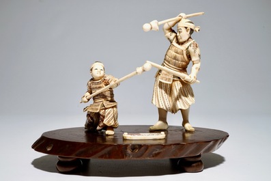 A Japanese ivory group of a warrior and his pupil, on a wooden base, Meiji, signed