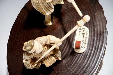 A Japanese ivory group of a warrior and his pupil, on a wooden base, Meiji, signed
