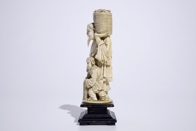 A Chinese ivory group of a peach picker on wooden base, early 20th C.
