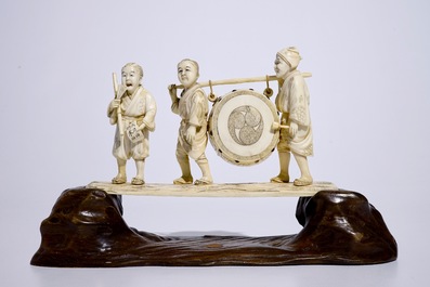 Een grote Japanse ivoren okimono van trommelende jongens op houten basis, Meiji, eind 19e eeuw, gesigneerd