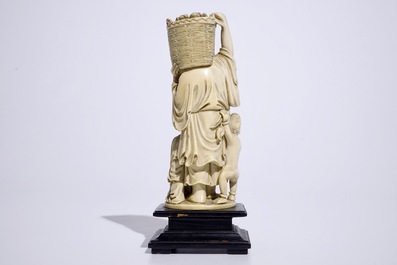A Chinese ivory group of a peach picker on wooden base, early 20th C.