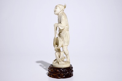 A Japanese ivory okimono of a fisherman on wooden base, Meiji, 19th C., signed