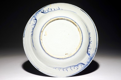 Un plat en porcelaine de Chine bleu et blanc &agrave; d&eacute;cor de figures dans un paysage, &eacute;poque Transition