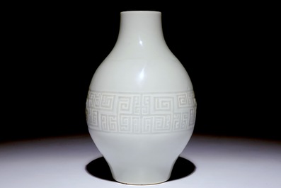 A Chinese monochrome white-glazed olive-shaped vase with underglaze design, Qianlong mark,  19th C.