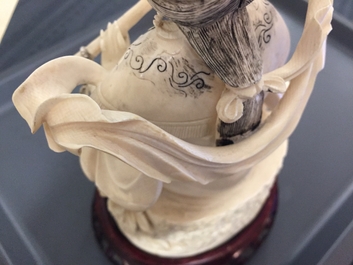 A Chinese ivory figure of a lady playing a flute on wooden base, early 20th C.