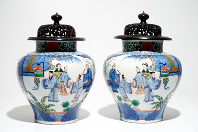 A pair of Chinese wucai baluster vases with carved lids and bases, 19th C.