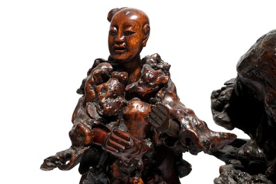 A large Chinese carved root wood group with a Luohan, 19th C.
