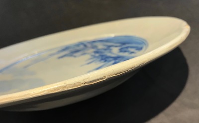 A Dutch Delft blue and white armorial dish dated 1683 and a blue and white landscape plate, 17th C.