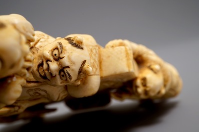 A Japanese carved ivory okimono with oni around a screen, signed, Meiji, 19th C.
