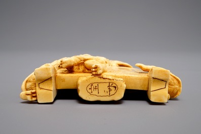 A Japanese carved ivory okimono with oni around a screen, signed, Meiji, 19th C.