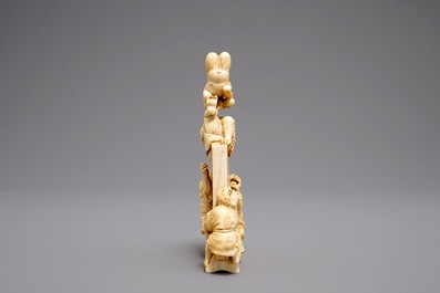 A Japanese carved ivory okimono with oni around a screen, signed, Meiji, 19th C.