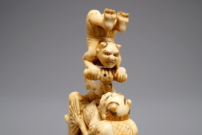 A Japanese carved ivory okimono with oni around a screen, signed, Meiji, 19th C.