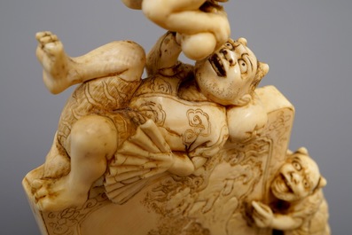 A Japanese carved ivory okimono with oni around a screen, signed, Meiji, 19th C.