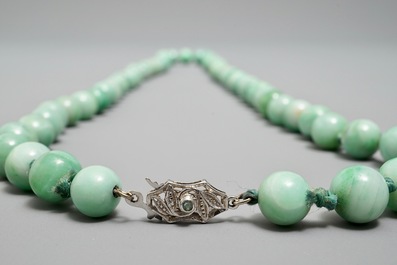 Two Chinese green jade beads necklaces, one with silver lock, 19/20th C.