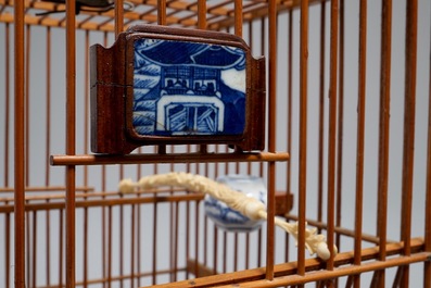 A Chinese wooden bird cage with ivory and porcelain ornaments, 19/20th C.