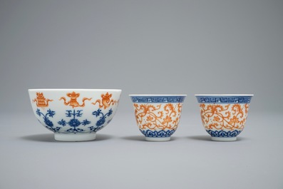A pair of Chinese iron red and blue cups and a bowl, Qianlong and Guangxu marks, 19/20th C.