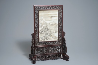 Un &eacute;cran de table en bois sculpt&eacute; mont&eacute; d'une plaque &agrave; d&eacute;cor d'un paysage hivernale d'apr&egrave;s He Xuren, 20&egrave;me