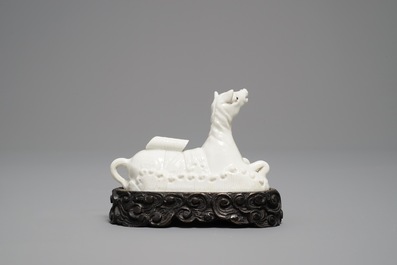 Un mod&egrave;le d'un cheval en porcelaine blanc de Chine de Dehua sur socle sculpt&eacute;, Kangxi