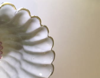 A Chinese famille rose lotus-shaped relief-decorated cup and saucer, Yongzheng