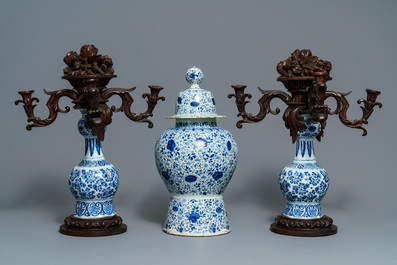 A Dutch Delft blue and white three-piece garniture with carved wooden candleholders, 18th C.
