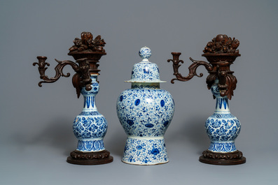 A Dutch Delft blue and white three-piece garniture with carved wooden candleholders, 18th C.