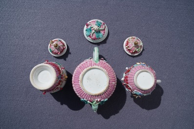 A Chinese famille rose relief-decorated teapot, milk jug and tea caddy on stands, Yongzheng