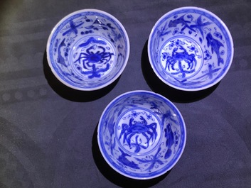 Six Chinese celadon and blue and white 'crabs and fish' cups and saucers, Kangxi