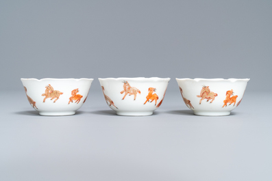 Three Chinese iron red eggshell cups and saucers with boys and goats, Yongzheng