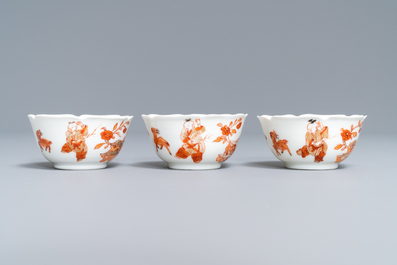 Three Chinese iron red eggshell cups and saucers with boys and goats, Yongzheng