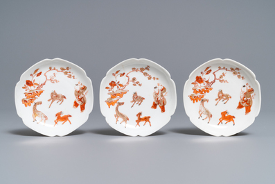 Three Chinese iron red eggshell cups and saucers with boys and goats, Yongzheng