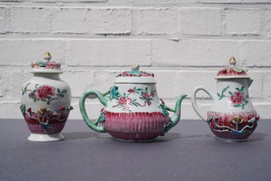 A Chinese famille rose relief-decorated teapot, milk jug and tea caddy on stands, Yongzheng