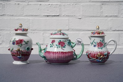 A Chinese famille rose relief-decorated teapot, milk jug and tea caddy on stands, Yongzheng