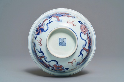 Een Chinese blauw-witte en onderglazuur rode kom met tempelleeuwen, Qianlong merk en periode