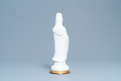A Chinese blanc de Chine figure of Guanyin on a gilt bronze base, 18/19th C.
