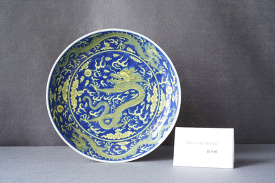 Un plat en porcelaine de Chine en bleu et jaune &agrave; d&eacute;cor d'un dragon, marque et &eacute;poque de Qianlong