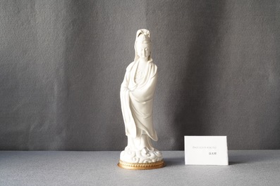 A Chinese blanc de Chine figure of Guanyin on a gilt bronze base, 18/19th C.