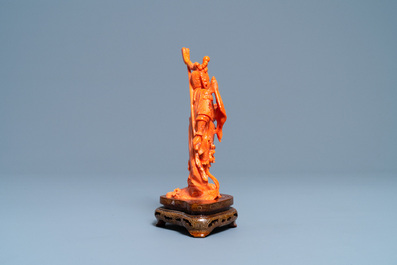 A Chinese carved red coral figure of a warrior holding a flag, 19/20th C.