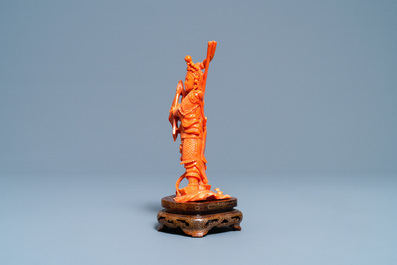 A Chinese carved red coral figure of a warrior holding a flag, 19/20th C.