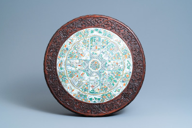 A Chinese carved wooden table with a large Canton famille verte plaque, 19th C.