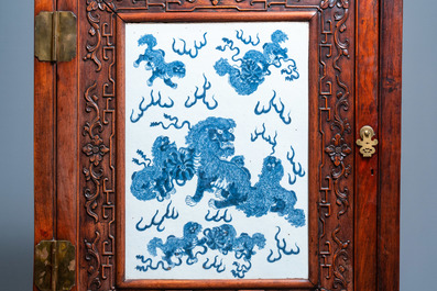 A Chinese hongmu cupboard with a blue and white 'Buddhist lions' plaque, 19th C.