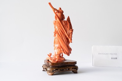 A Chinese carved red coral figure of a warrior holding a flag, 19/20th C.