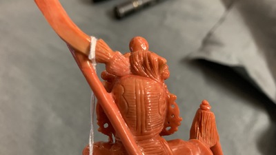 A Chinese carved red coral figure of a warrior holding a flag, 19/20th C.