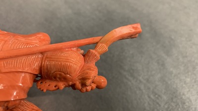 A Chinese carved red coral figure of a warrior holding a flag, 19/20th C.