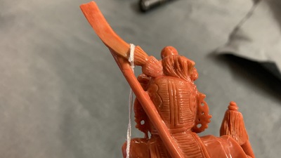 A Chinese carved red coral figure of a warrior holding a flag, 19/20th C.