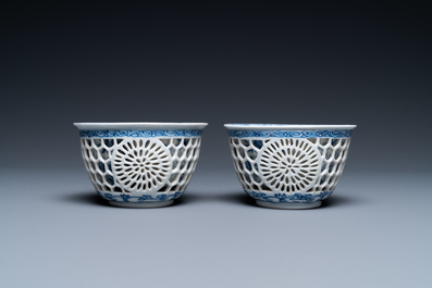 A pair of Chinese blue and white reticulated double-walled cups and saucers, Kangxi