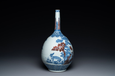 A Chinese blue, white and copper-red bottle vase with a deer and birds among blossoming branches, Daoguang