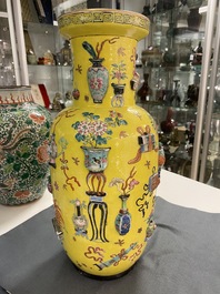 Een Chinese famille rose rouleau vaas met reli&euml;fdecor van antiquiteiten op gele fondkleur, 19e eeuw