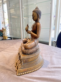 A large Tibetan brass and copper Buddha on throne, probably 16th C.