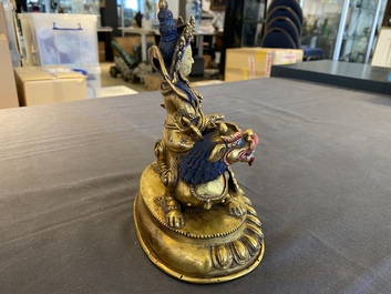A Tibetan gilt bronze group of Jambhala on his lion, 19/20th C.